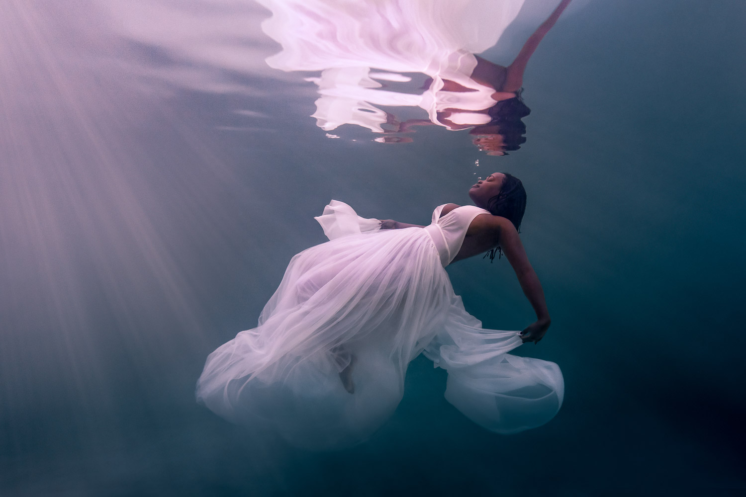 underwater woman photoshoot with bride wearing wedding dress in pool